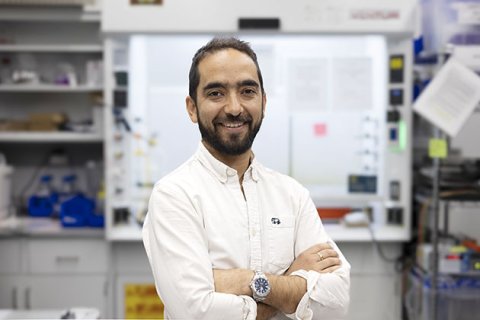 Juan-Pablo Correa-Baena poses in the foreground with the lab blurred in the background